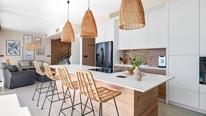 A modern kitchen with a central island, wicker pendant lights, and a dining area with wicker chairs. - Ocean View Villa: Your Dream Getaway (Jesenice, Dugi Rat)