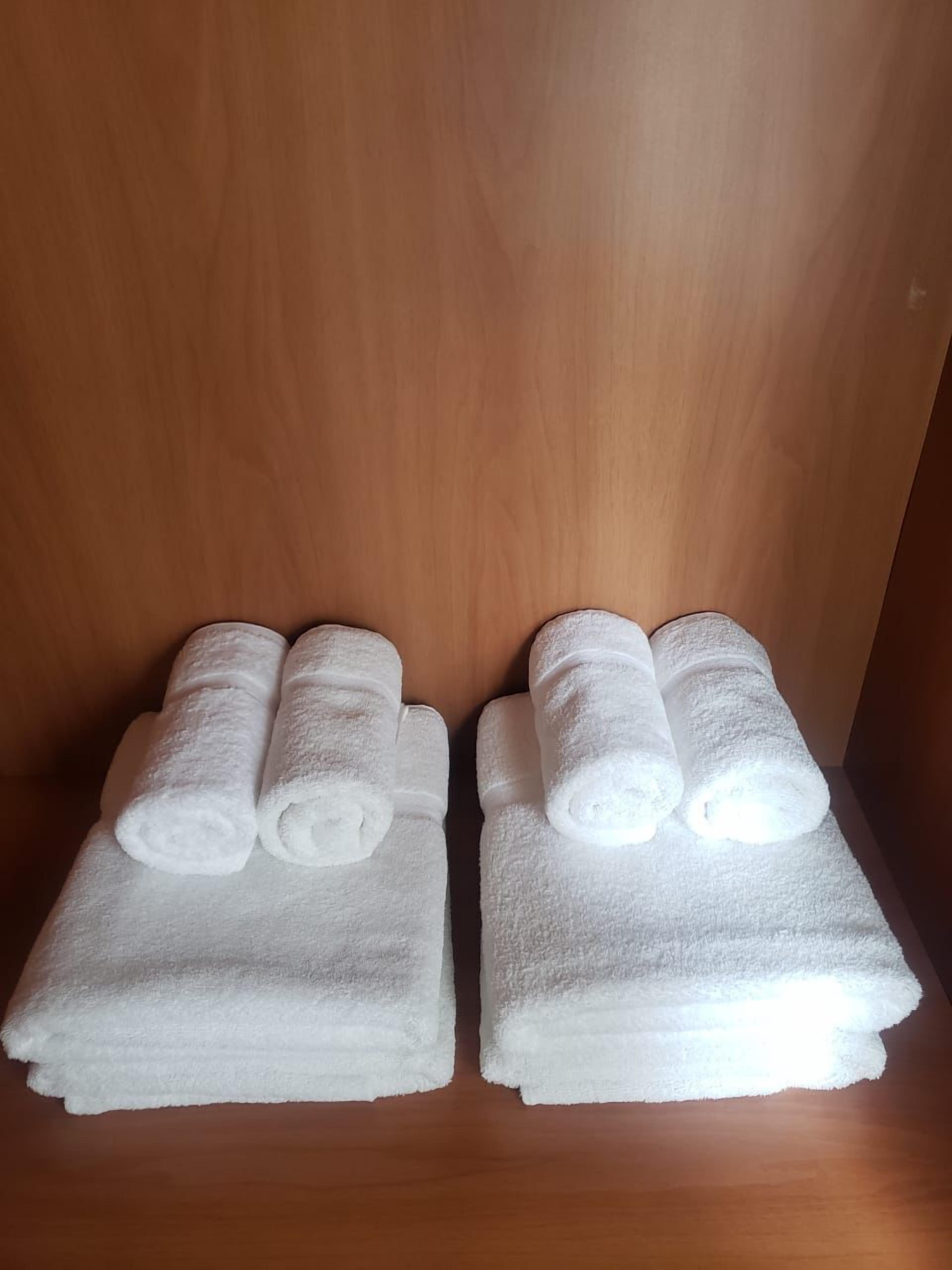 Two neatly folded white towels stacked on a wooden surface.