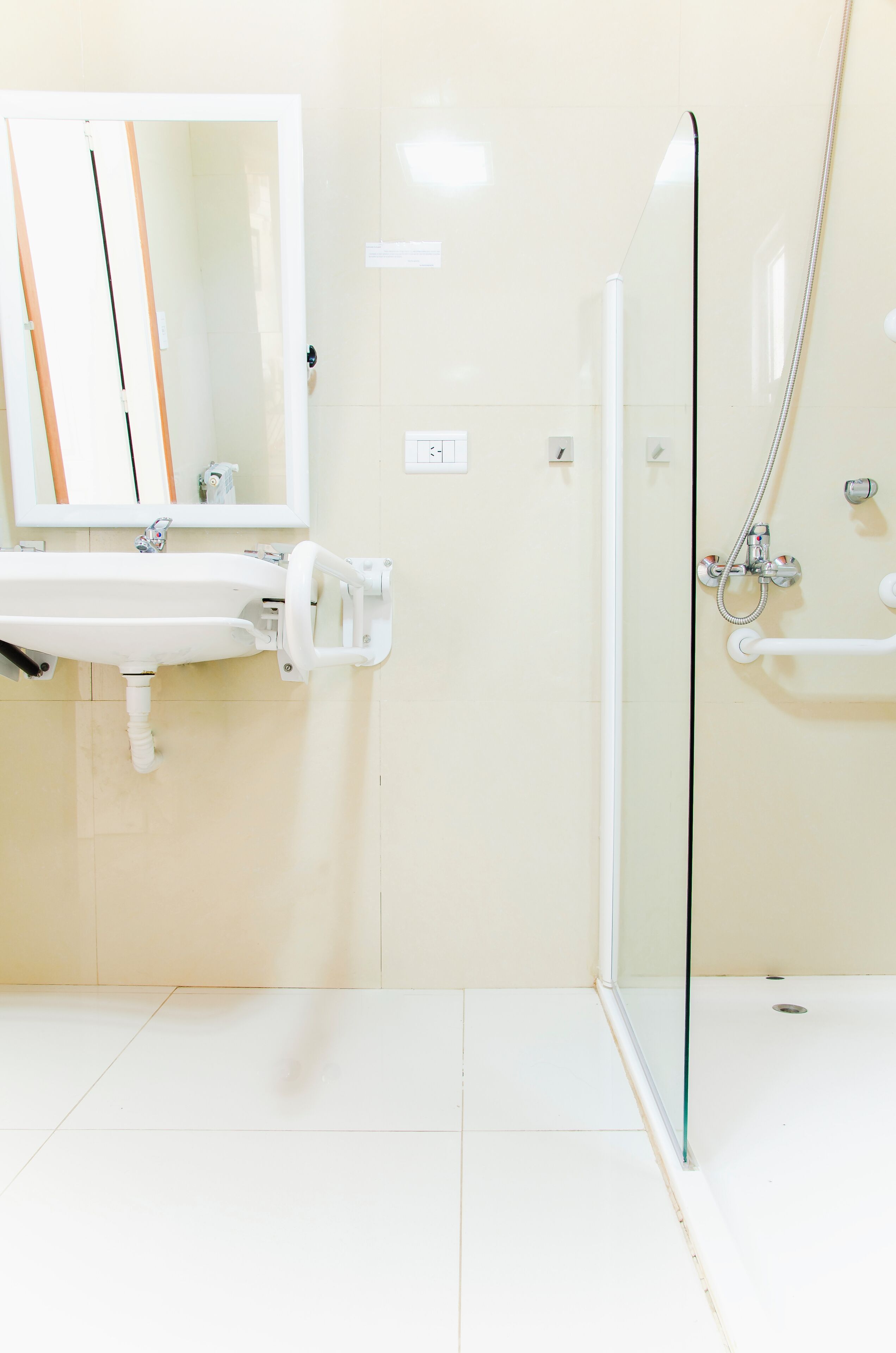 A bathroom with a white sink, mirror, and glass shower enclosure.
