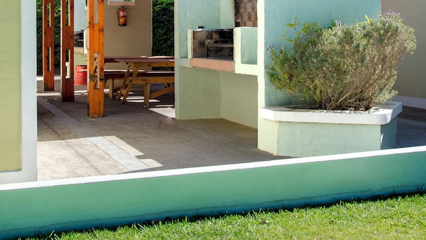 A covered outdoor area with a wooden pergola, a picnic table, and a small building with a light blue exterior. - Complejo 21 de Enero - Luz y Fuerza (Puerto Madryn)