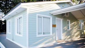 A small, light blue building with a white door and windows, a sign reading "Cabin 17", and a small porch area. - Complejo 21 de Enero - Luz y Fuerza (Puerto Madryn)