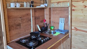 Une cuisine de taille réduite, équipée d’une cuisinière à gaz, d’un évier et de meubles de rangement en bois.