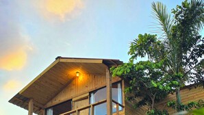 Une maison en bois dotée d’un balcon, entourée de végétation.