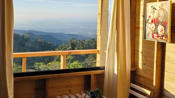 Une cabane en bois avec un balcon, une table, deux chaises et une plante en pot.
