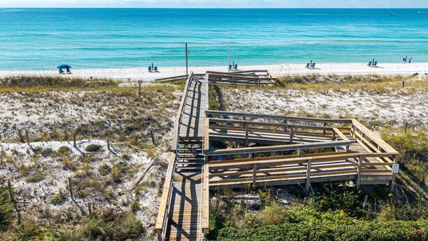 A beach with a wooden boardwalk leading to the shore, sandy dunes, and a clear blue ocean. - Aegean 214 Gorgeous 2 bed/2 bath (Destin)