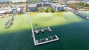 An aerial view of a marina with multiple docks and boats, surrounded by a resort with several buildings and a beach in the background. - Beautiful DW Gulfside 403 (Fort Walton Beach)