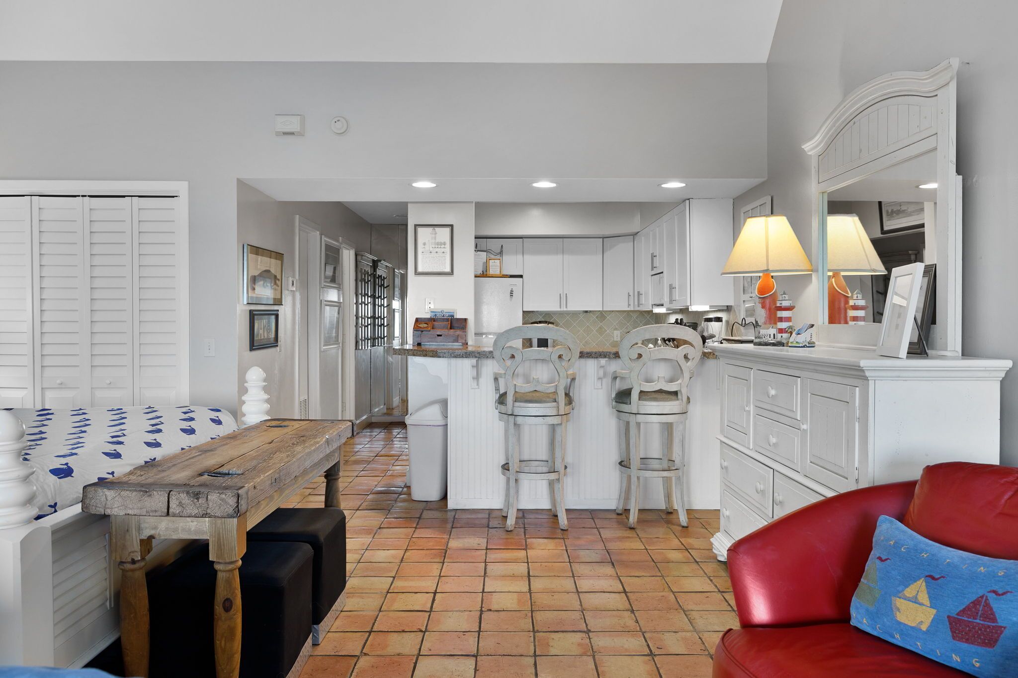 A compact kitchen with white cabinetry, a wooden dining table, and a red sofa.