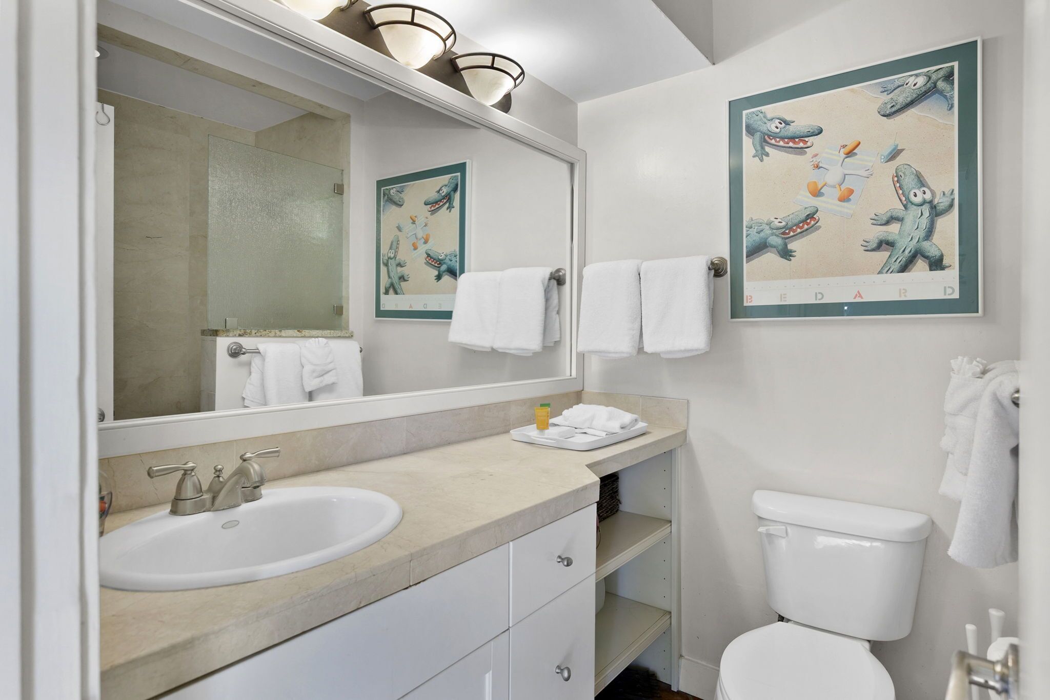 A bathroom with a sink, mirror, toilet, and towels.