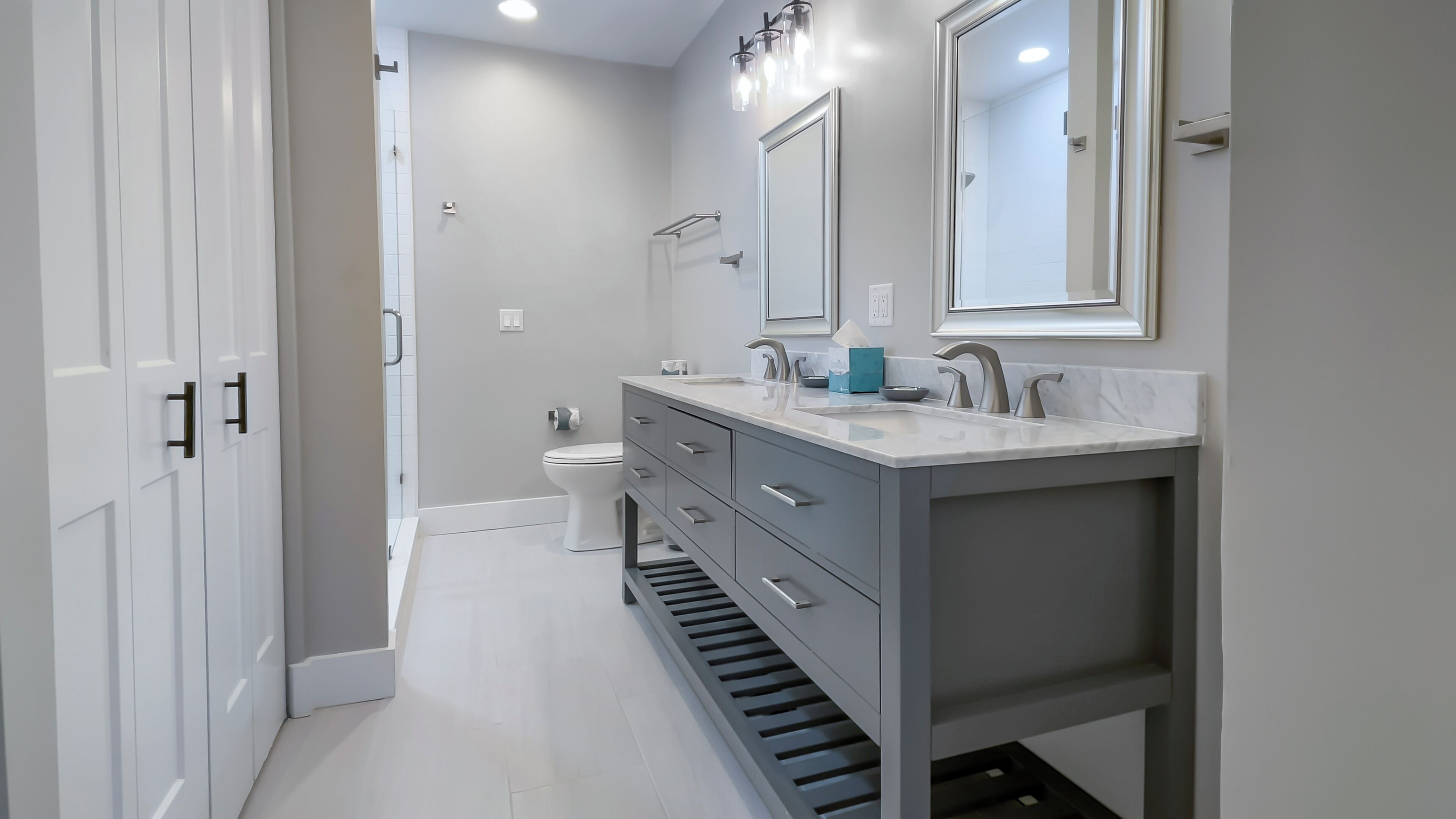 A modern bathroom with a white toilet, a vanity with a sink and mirror, and a shower area.