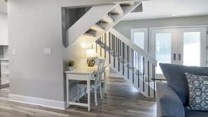 A modern kitchen with a dining area, a staircase, and a living room with a sofa.