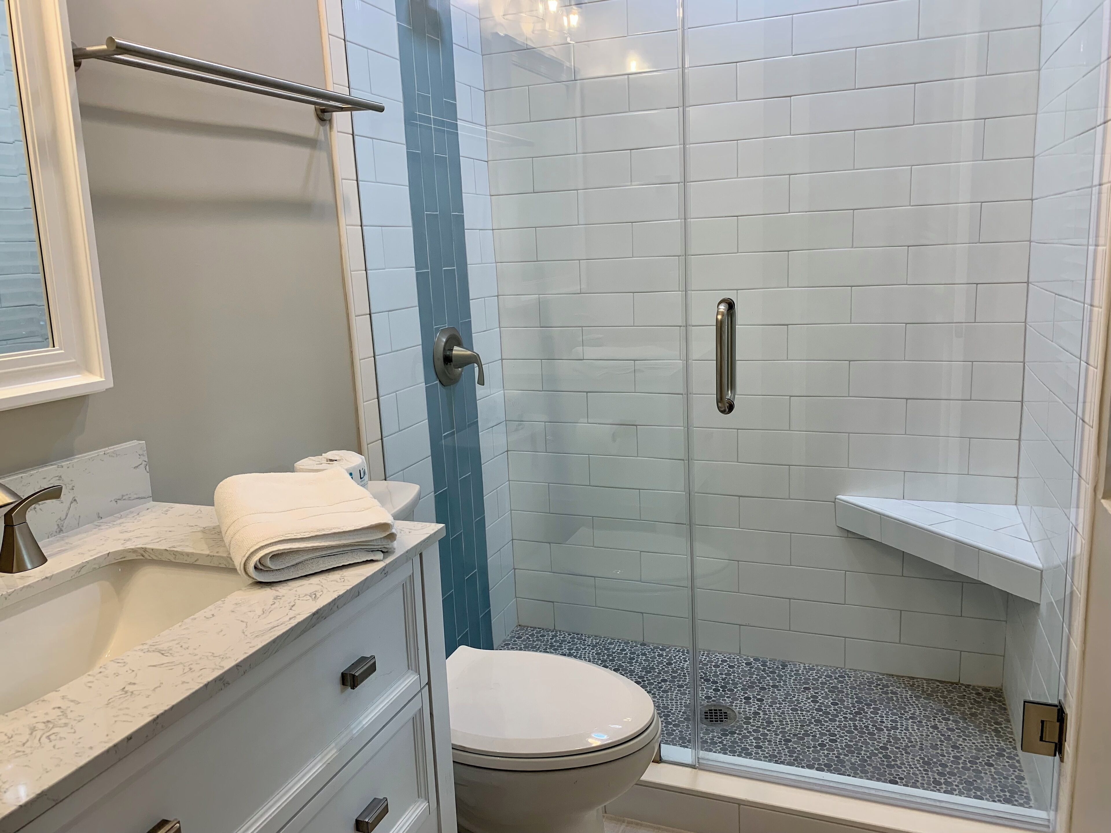A bathroom with a marble sink, a toilet, and a glass-enclosed shower area.