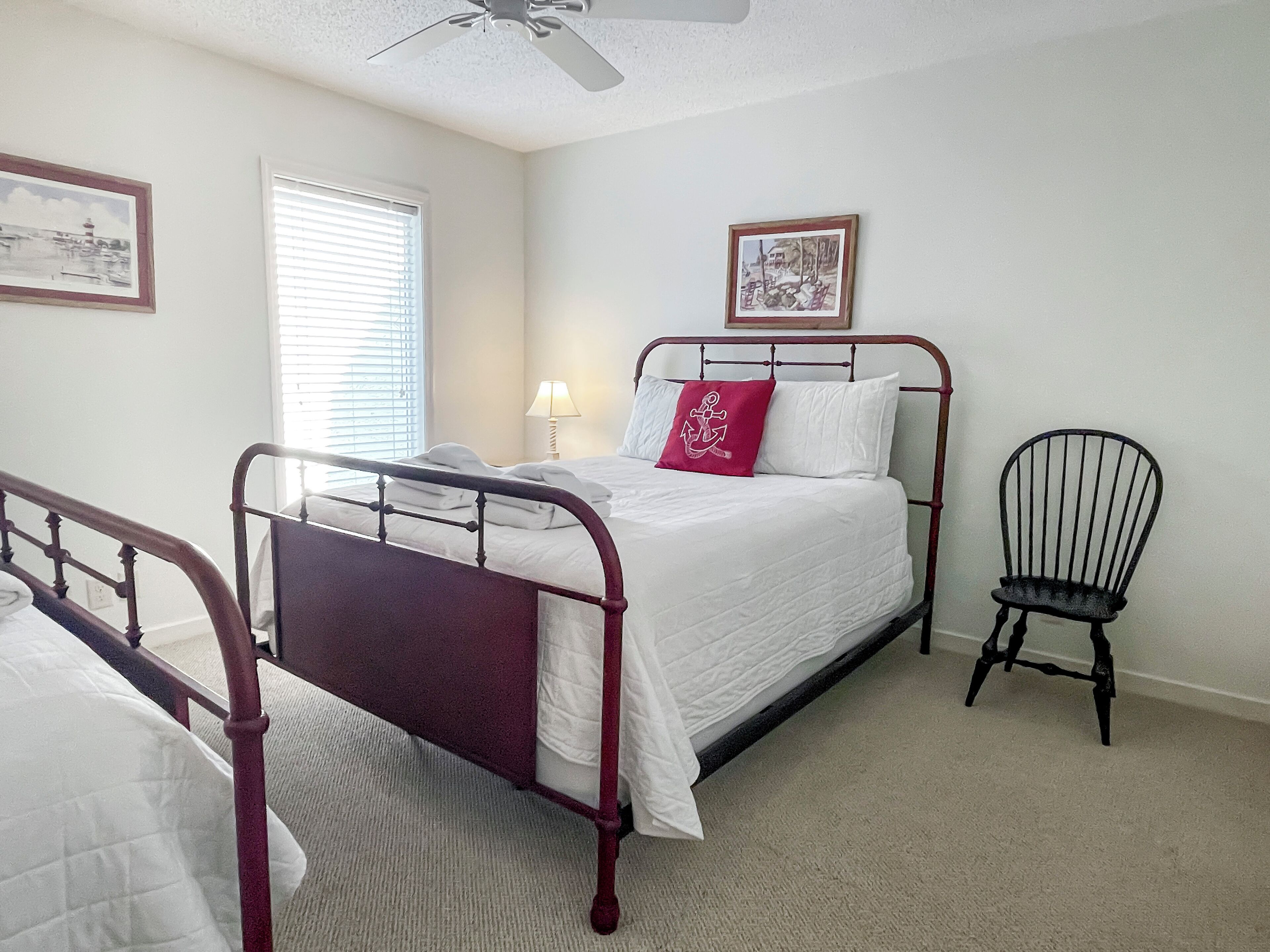 A bedroom with a bed, a chair, and two framed pictures on the wall.