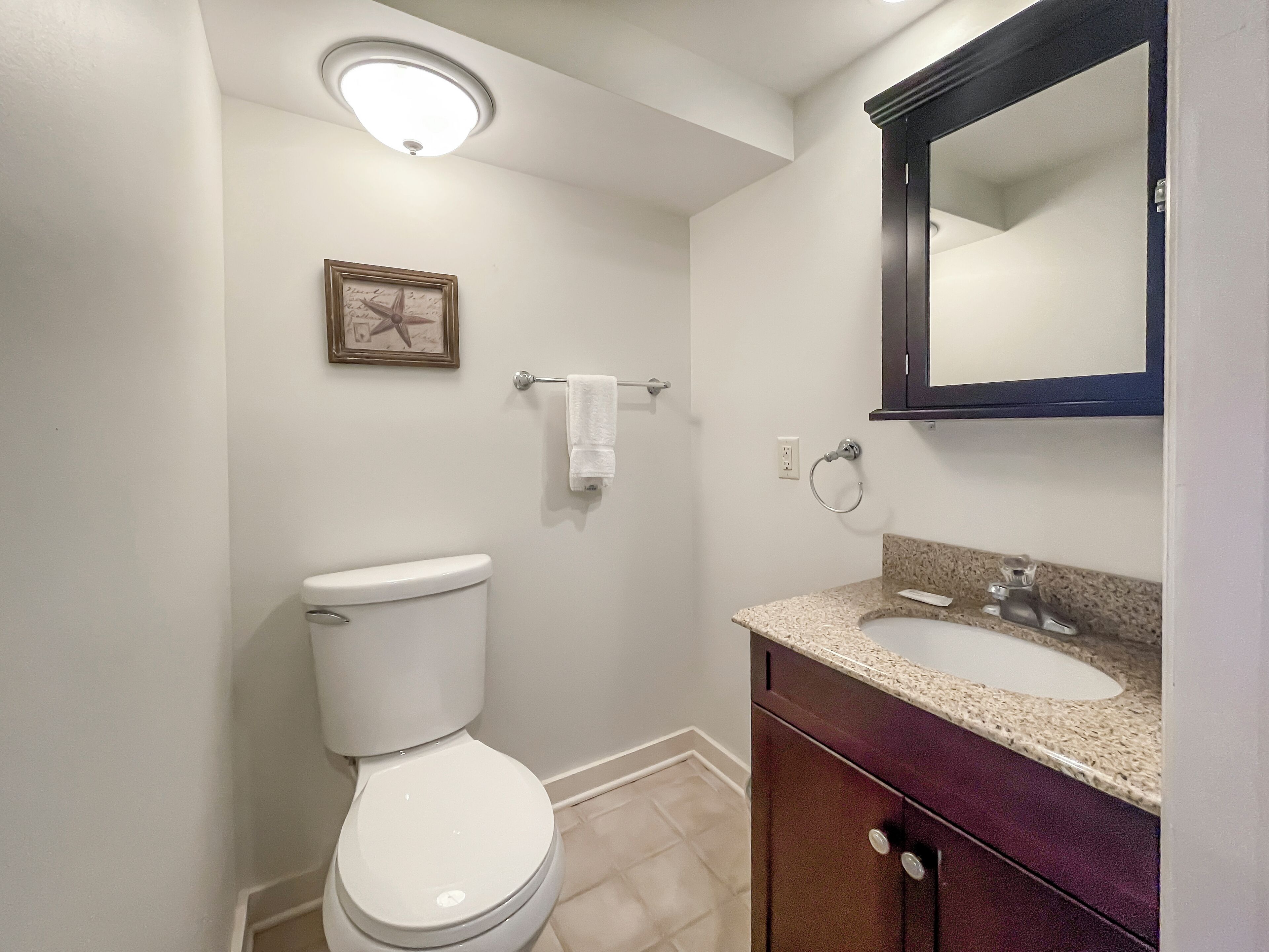 A bathroom with a toilet, a sink, a mirror, and a towel rack.