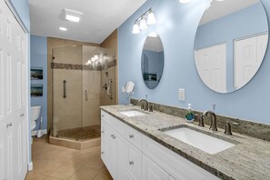 A bathroom with a shower, two sinks, a large mirror, and a toilet. - 490 Plantation Club Villas at The Sea Pines Resort (Hilton Head Island)