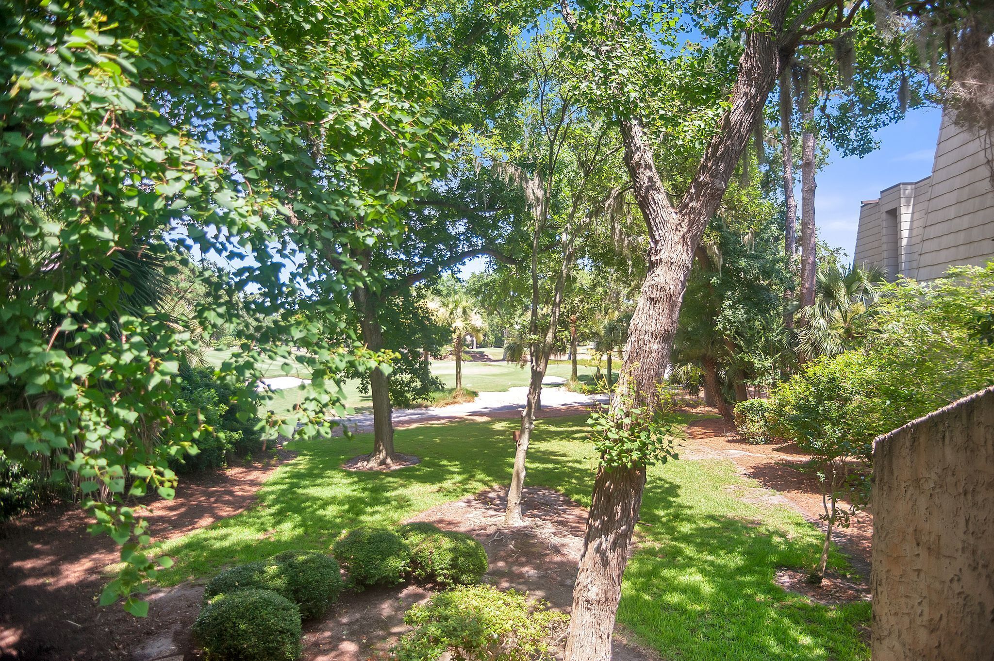 A well-maintained garden with mature trees, a grassy lawn, and a paved path.
