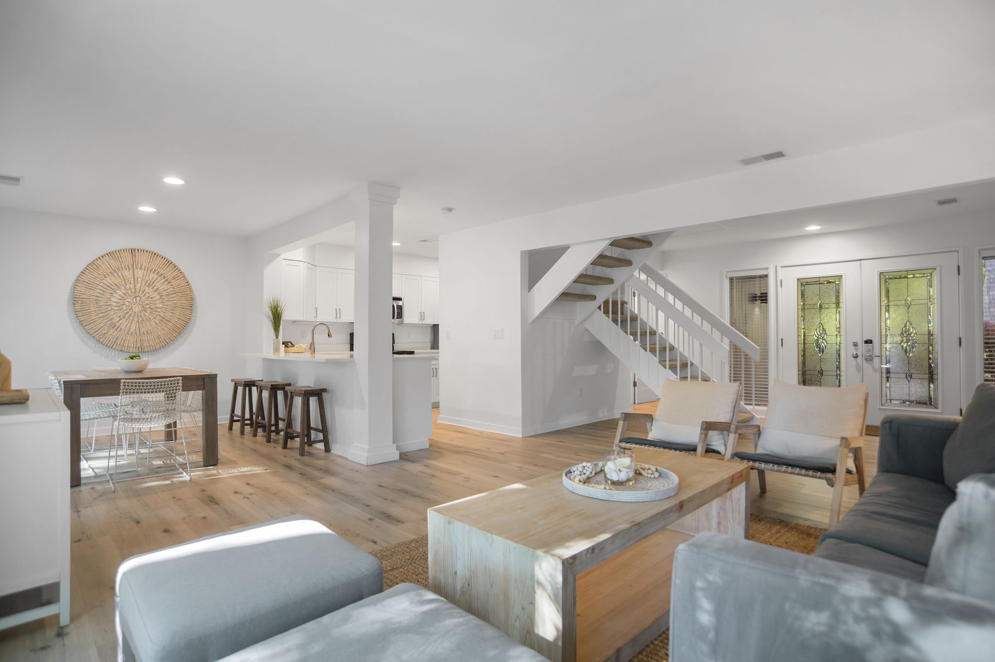 Un amplio salón con una escalera, una mesa de comedor y una cocina al fondo.