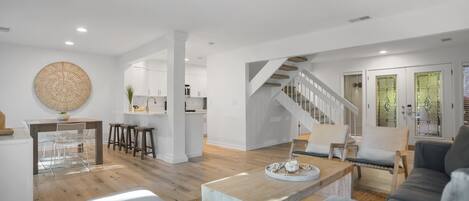 Un amplio salón con una escalera, una mesa de comedor y una cocina al fondo.