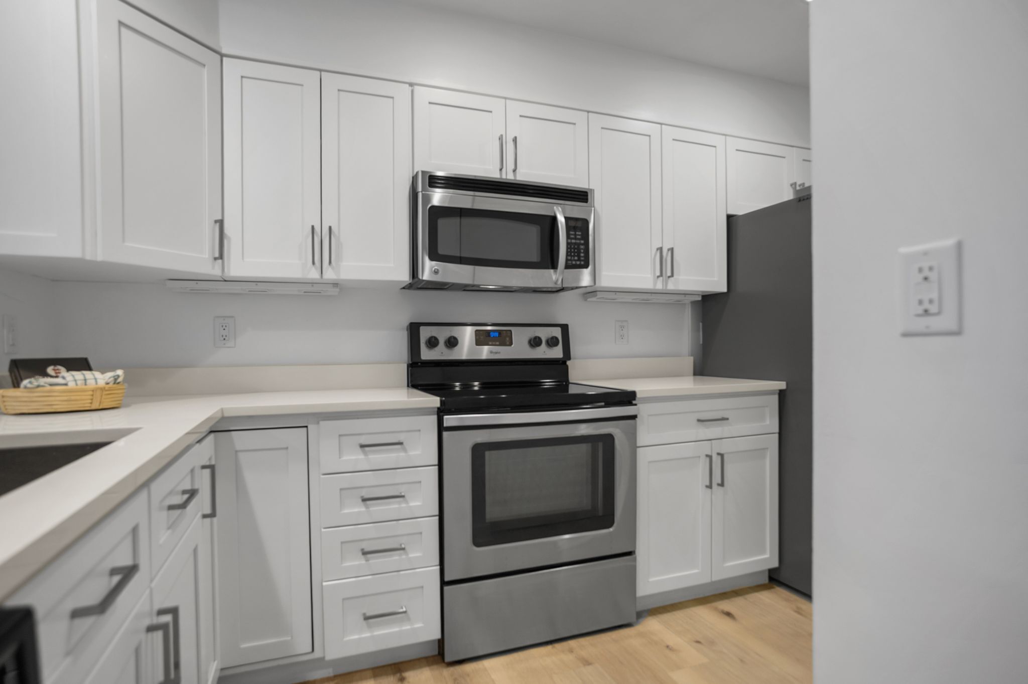A modern kitchen with white cabinetry, a stainless steel microwave, a built-in oven, and a black stovetop.