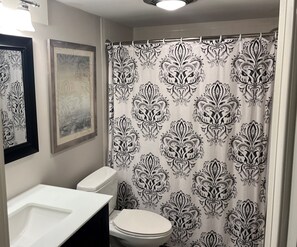 Een badkamer met toilet, wastafel en douchegordijn met een zwart-wit patroon.