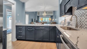 A modern kitchen with dark cabinets, a large island, and a stainless steel sink.
