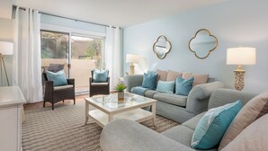 A living room with a sofa, armchairs, a glass coffee table, and a view through a sliding glass door to an outdoor area. - 828 Ketch Court at The Sea Pines Resort (Hilton Head Island)
