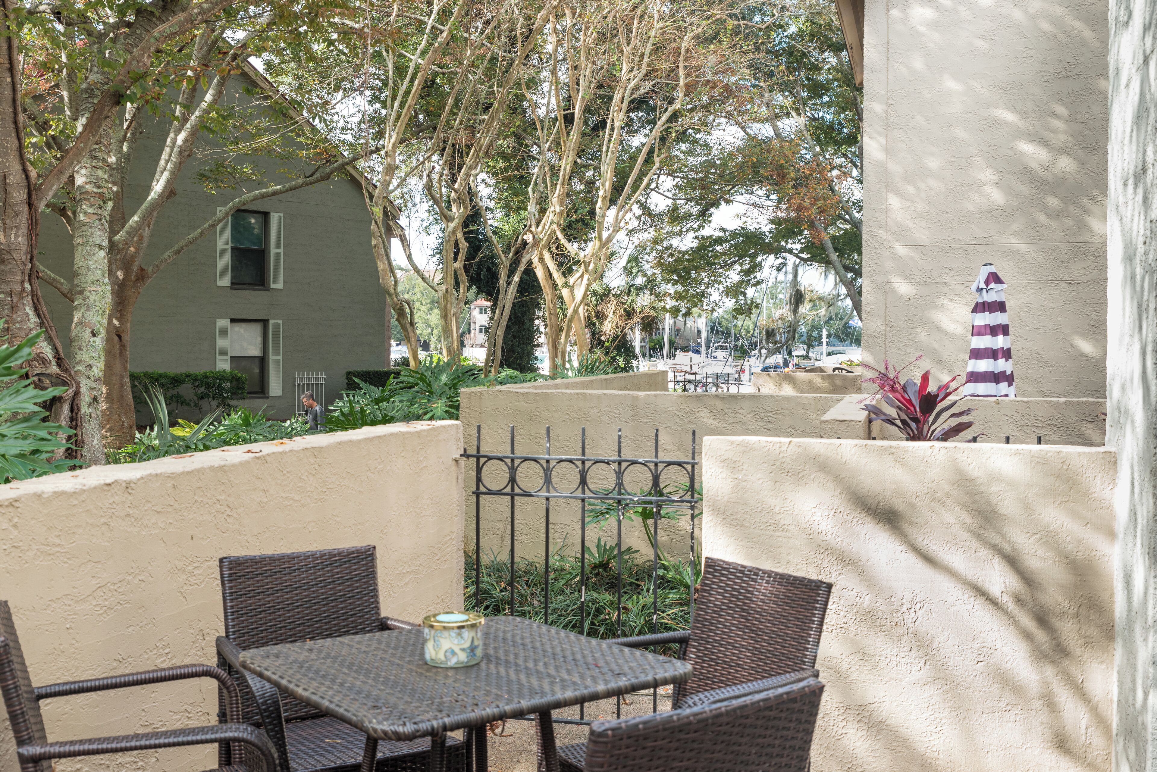 Une terrasse extérieure aménagée avec des meubles en osier, une table et un parasol décoratif.