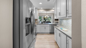 A modern kitchen with stainless steel appliances, light-colored cabinets, and a view of the outdoors. - 485 Plantation Club Villas at The Sea Pines Resort (Hilton Head Island)