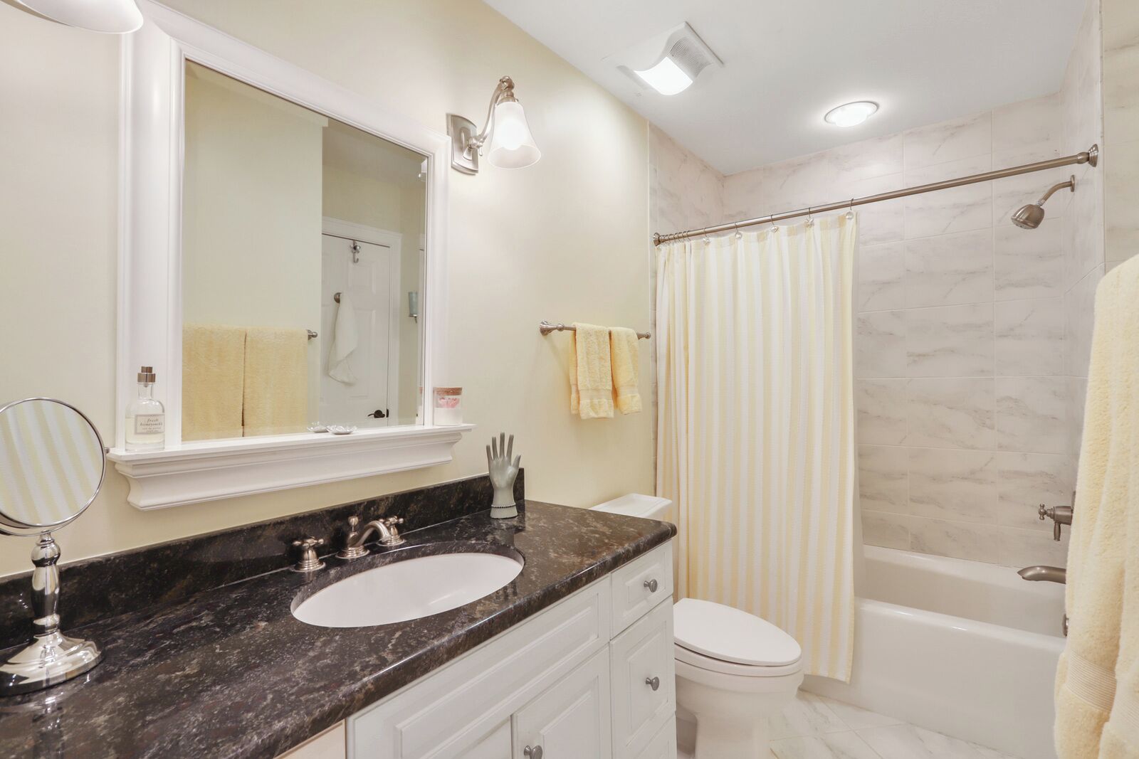Une salle de bain avec un lavabo en marbre, des toilettes, une baignoire et un rideau de douche.