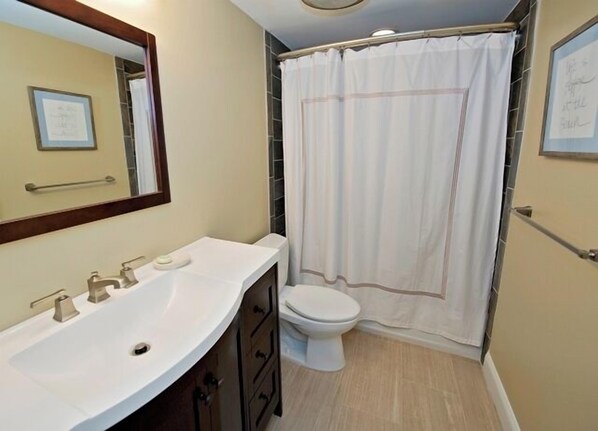 Un baño con lavamanos blanco, inodoro y cortina de ducha.