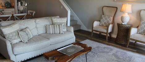 A living room with a sofa, chairs, a coffee table, and a lamp.