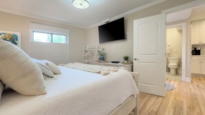 A bedroom with a bed, a TV mounted on the wall, and a door leading to a bathroom. - 804 Clipper Court at The Sea Pines Resort (Hilton Head Island)
