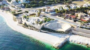 An aerial view of a coastal area with a large stadium, beachfront, and residential buildings. - Iris Apartment - comfort e stile (Bisceglie)