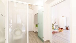 A hallway with a glass door leading to a room with a bed, a small table, and a plant. - Iris Apartment - comfort e stile (Bisceglie)