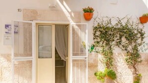 A room with a partially open door, a window with a curtain, and potted plants against the wall. - Iris Apartment - comfort e stile (Bisceglie)