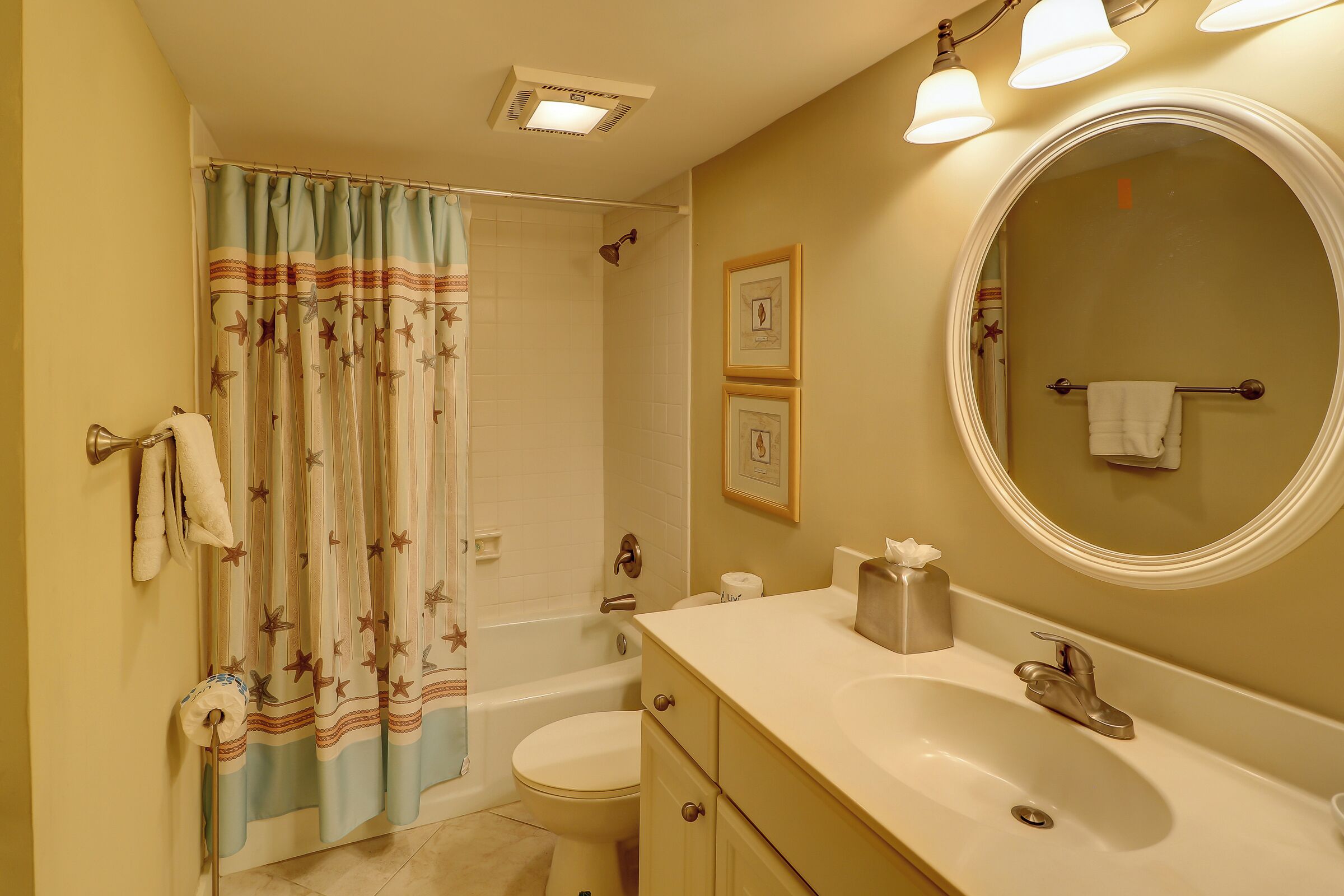 A bathroom with a bathtub, toilet, sink, and a large mirror.
