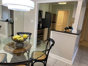 A dining area with a glass table, chairs, and a bowl of yellow fruits. - 838 Ketch Court at The Sea Pines Resort (Hilton Head Island)