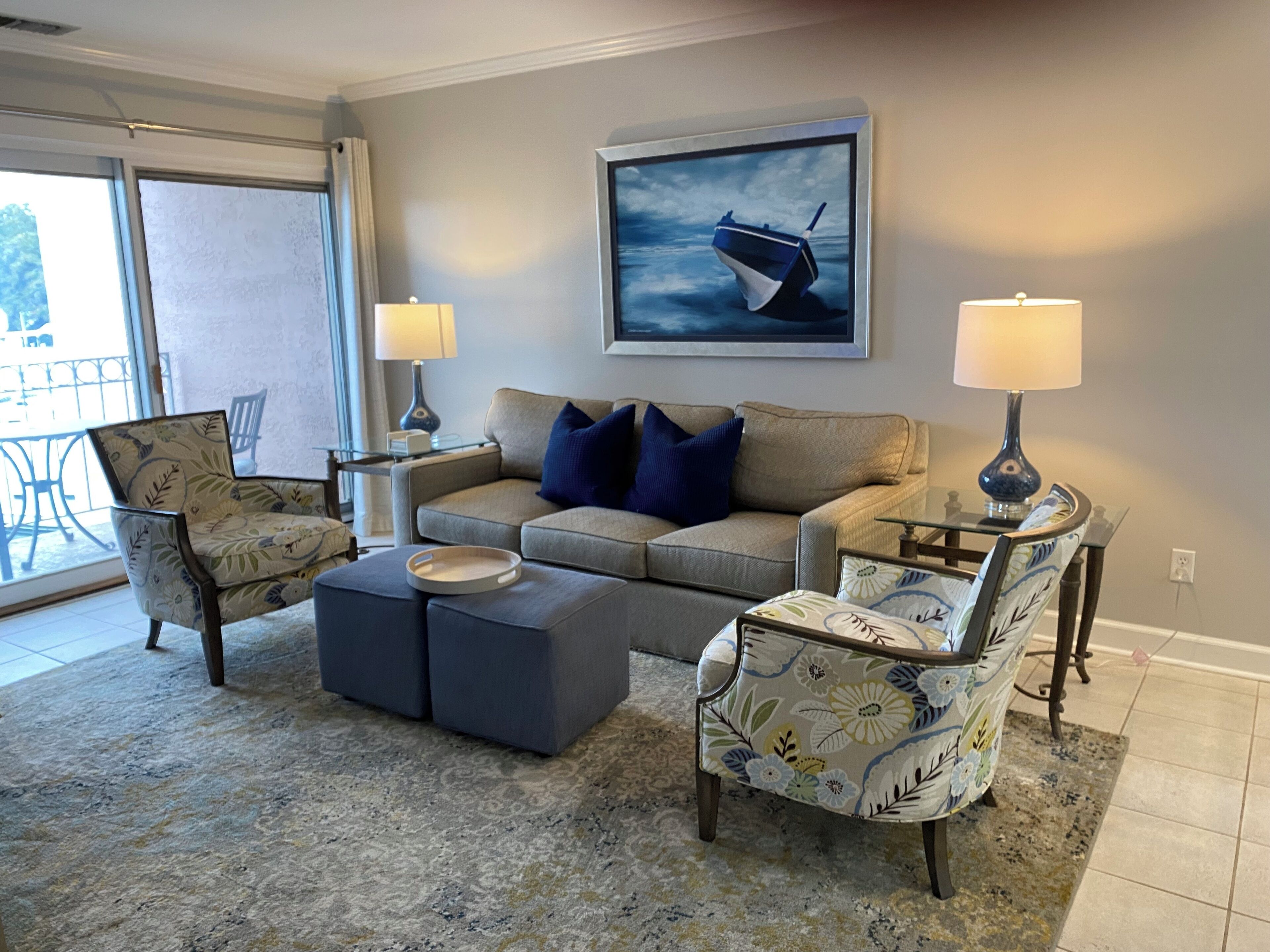 A living room with a sofa, two armchairs, a coffee table, and a painting of a boat on the wall.