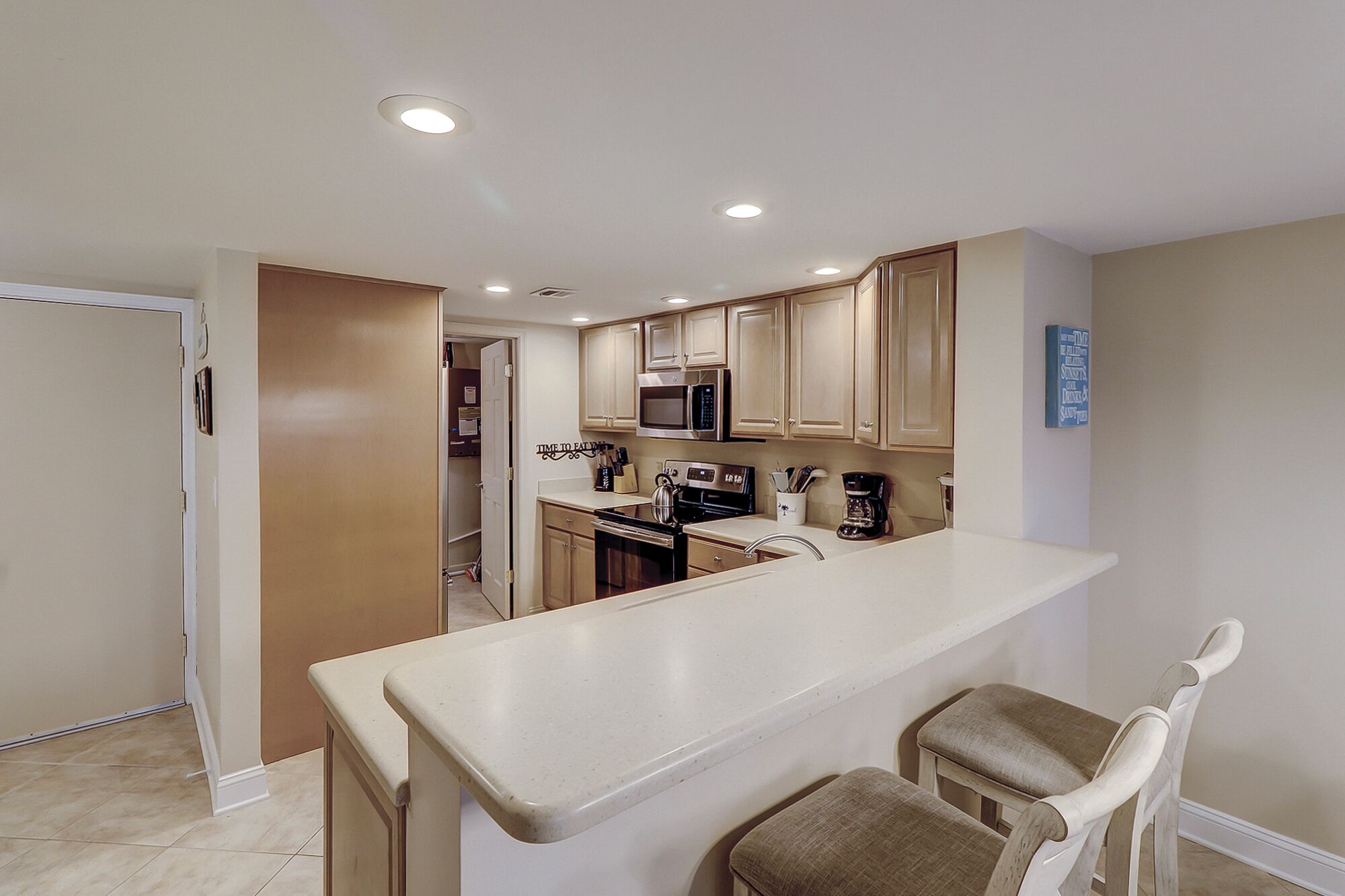 A modern kitchen with a central island, stainless steel appliances, and light-colored cabinetry.
