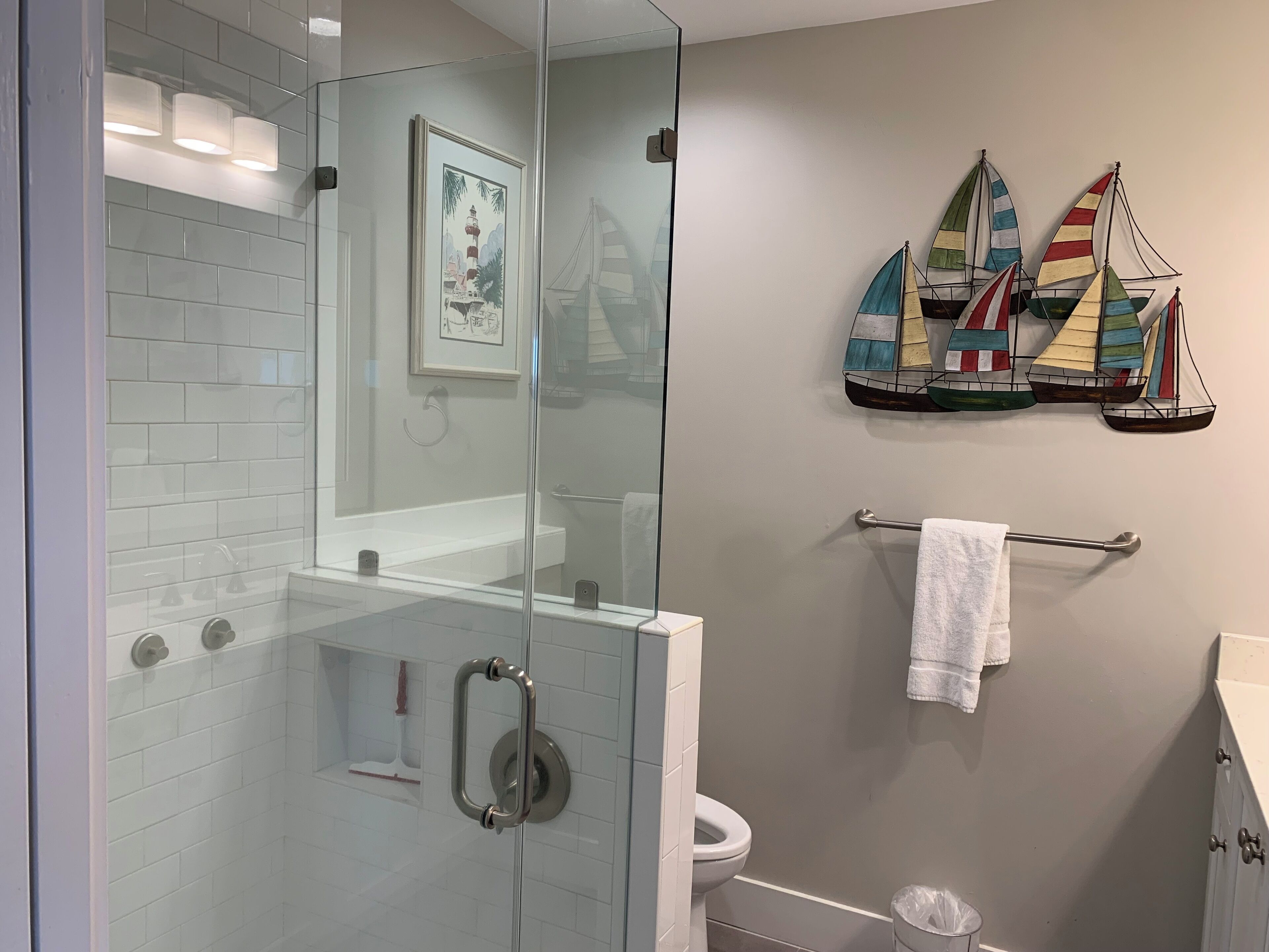 A bathroom with a glass shower enclosure, a white toilet, and a towel rack with a white towel.
