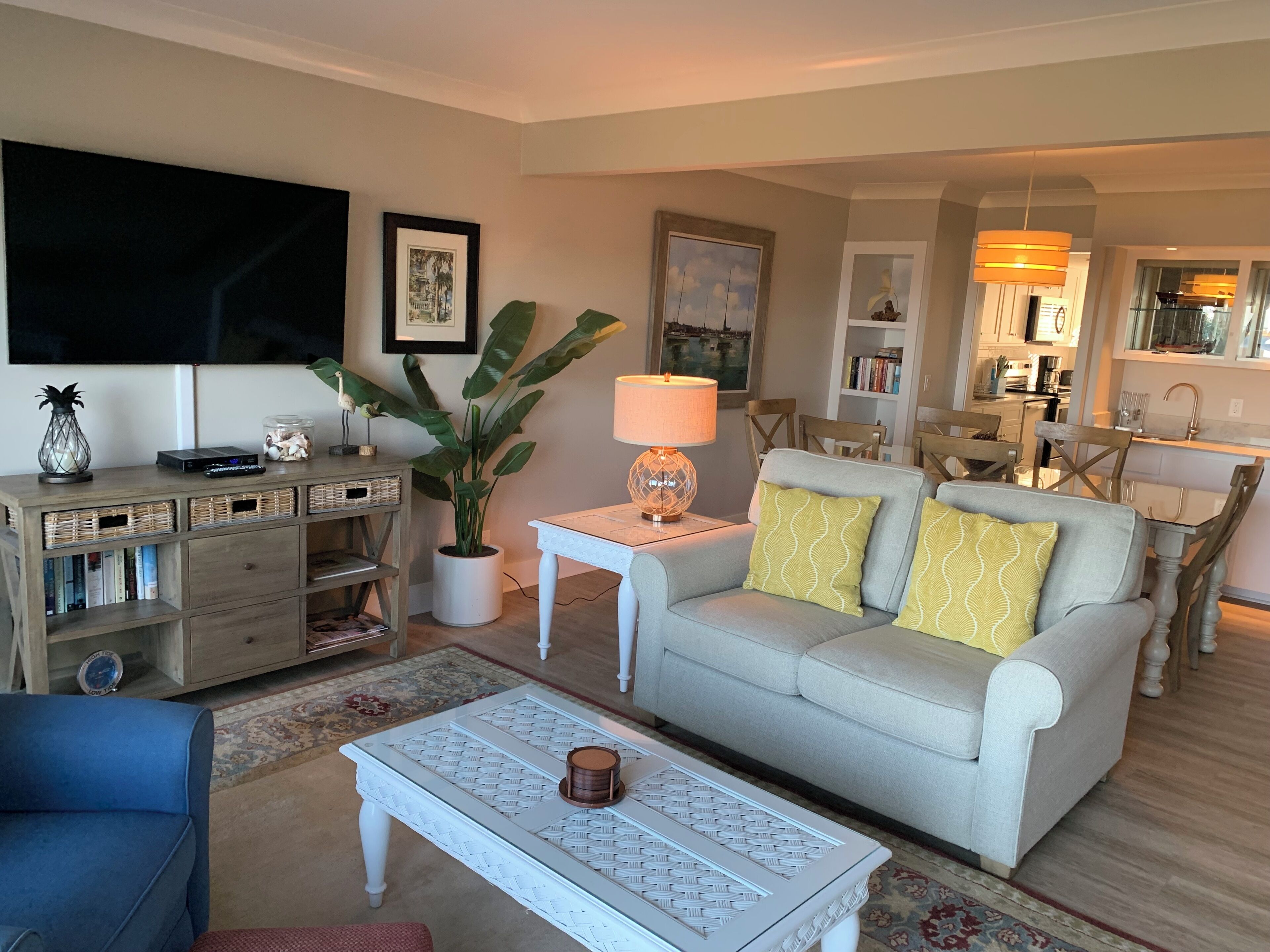 A living room with a sofa, coffee table, TV, and a dining area with chairs and a table.