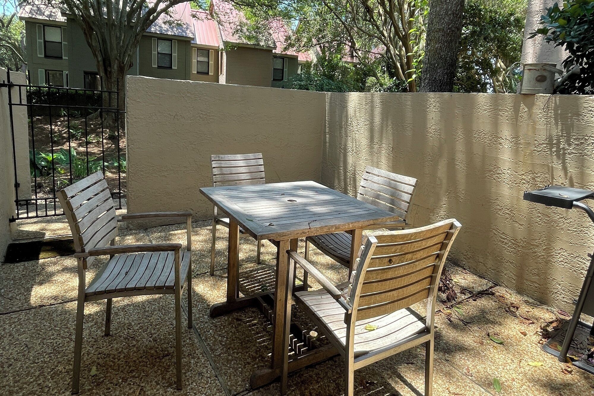An outdoor patio with a square table and four wooden chairs.