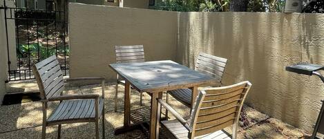 An outdoor patio with a square table and four wooden chairs.