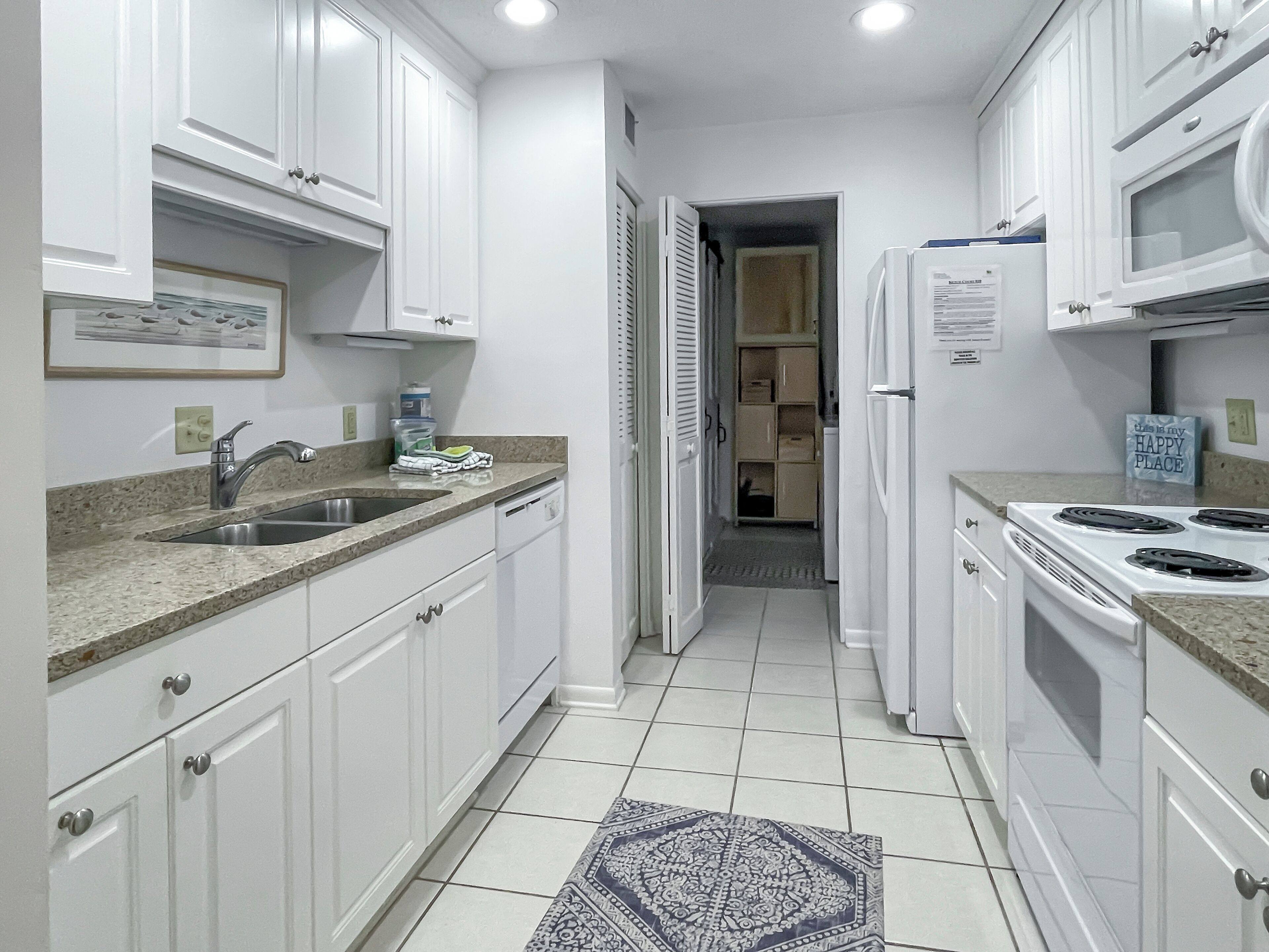 A modern kitchen with white cabinets, a granite countertop, a sink, a dishwasher, and a stove.