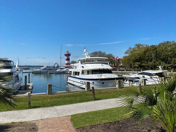 A marina with boats docked, a lighthouse, and a pathway leading to the water. - 841 Ketch Court at The Sea Pines Resort (Hilton Head Island)
