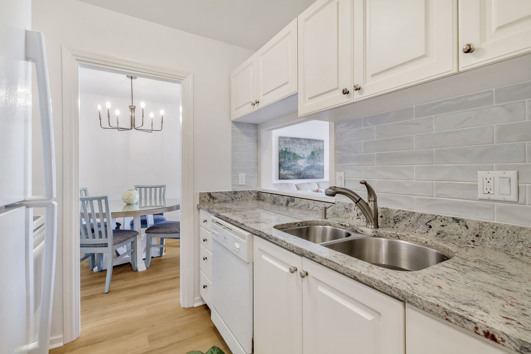 A modern kitchen with white cabinetry, granite countertops, and a double sink.