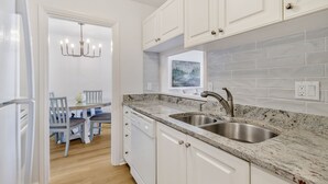 Een moderne keuken met witte kasten, granieten aanrecht en een dubbele spoelbak.