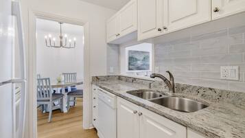 A modern kitchen with white cabinetry, granite countertops, and a double sink.
