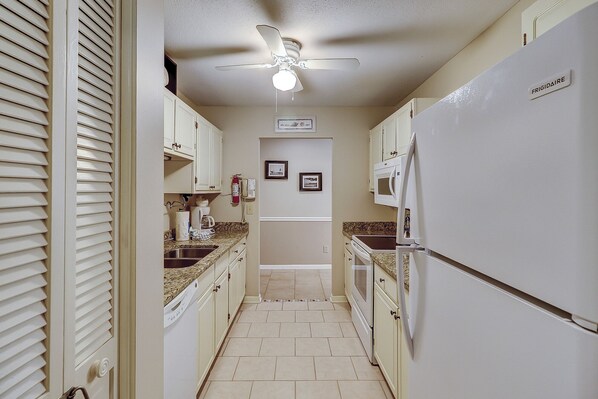 A narrow kitchen with white cabinets, a microwave, and a ceiling fan. - 929 Cutter Court at The Sea Pines Resort (Hilton Head Island)