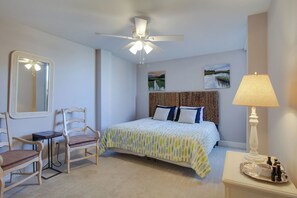 A bedroom with a bed, a desk, two chairs, a ceiling fan, and a lamp. - 1020 Caravel Court at The Sea Pines Resort (Hilton Head Island)
