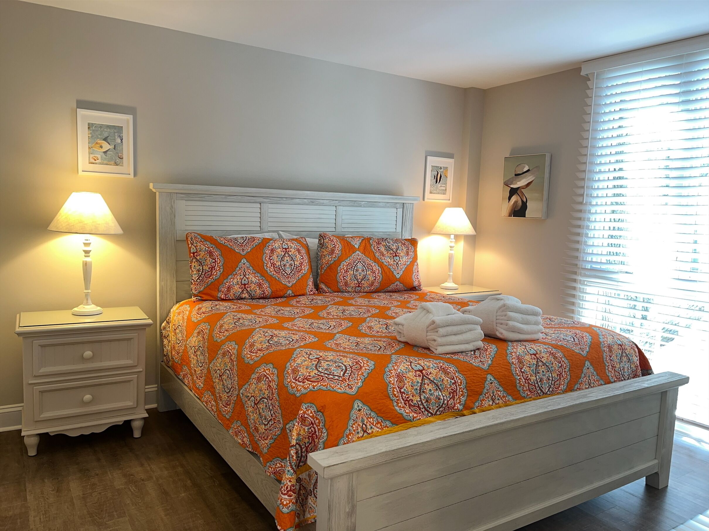 Une chambre à coucher avec un lit, deux tables de chevet et une fenêtre avec des stores.